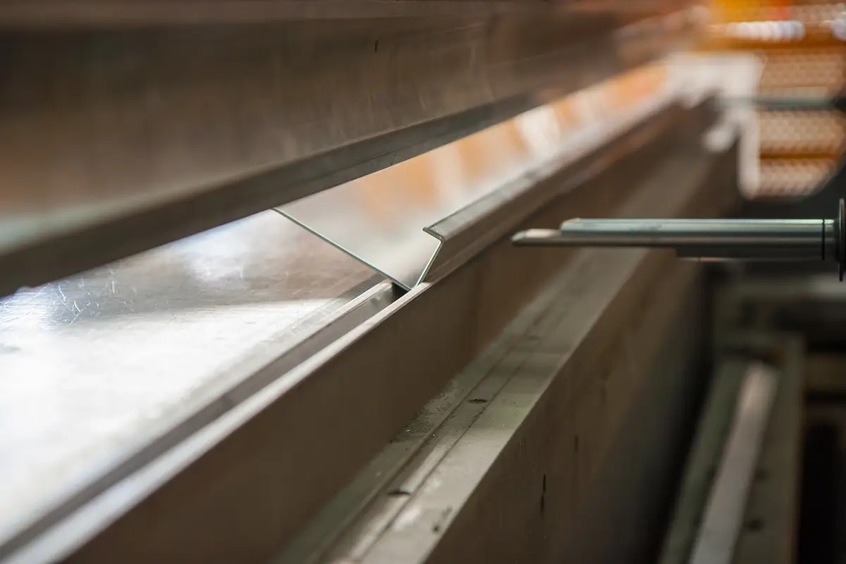 worker inspecting a roll form metal part on a factory floor