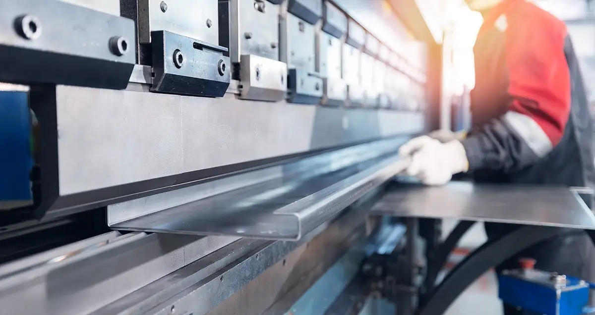 A section of sheet metal is pulled through a roll forming machine on a factory floor