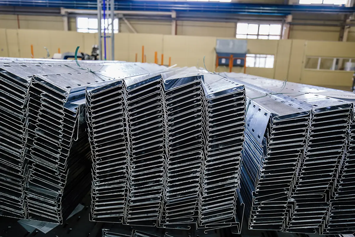 worker inspecting a roll form metal part on a factory floor