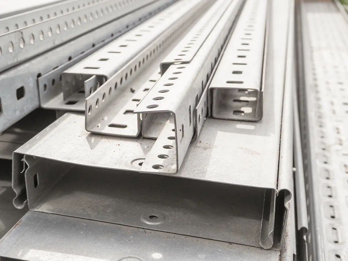 A section of sheet metal is pulled through a roll forming machine on a factory floor