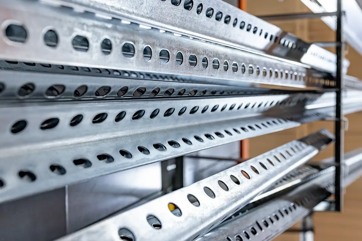 A section of sheet metal is pulled through a roll forming machine on a factory floor